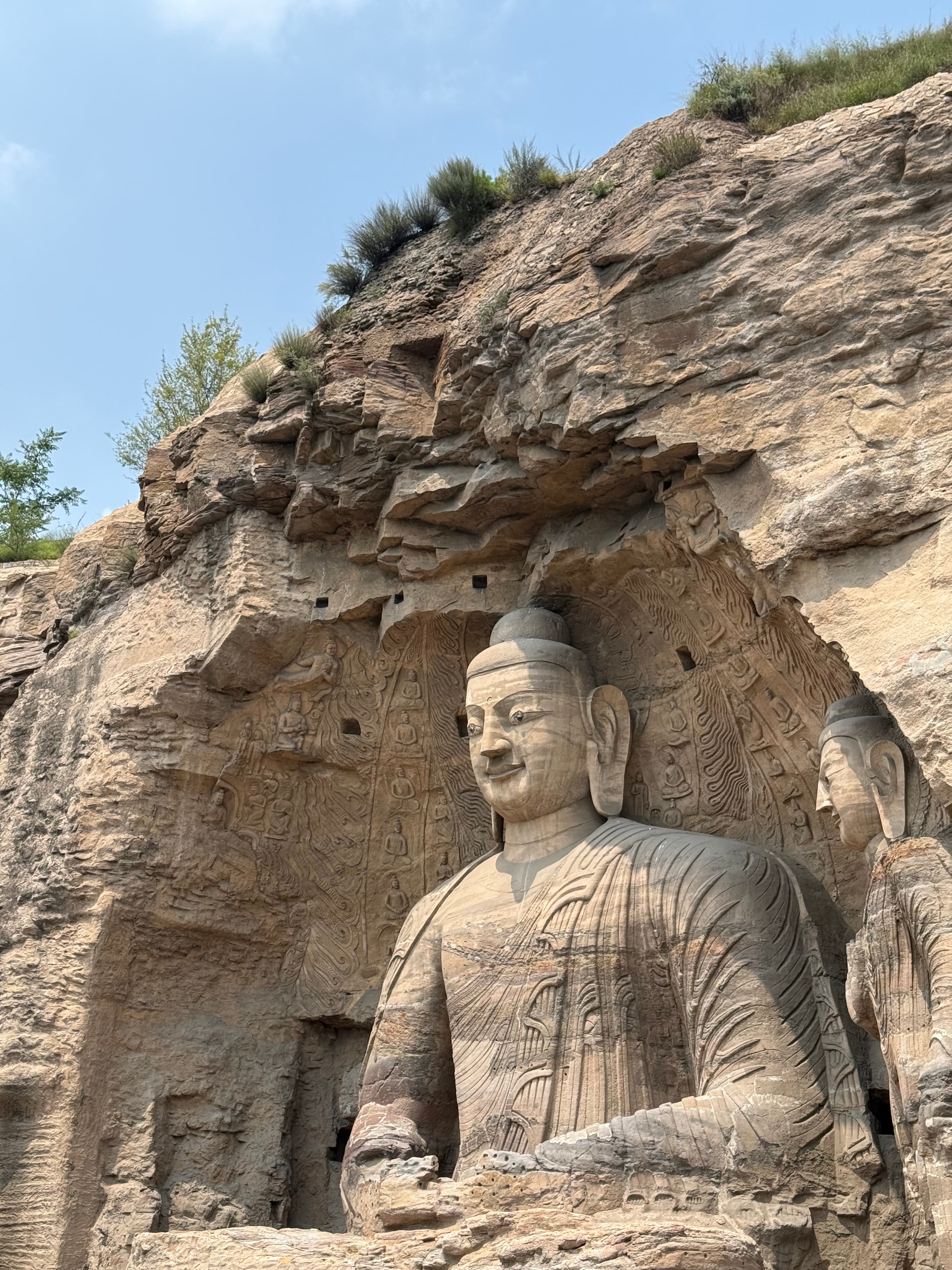 云冈石窟的大佛正面近景，抬手当胸、目光低垂，就这样看了一千五百年的人来人往。