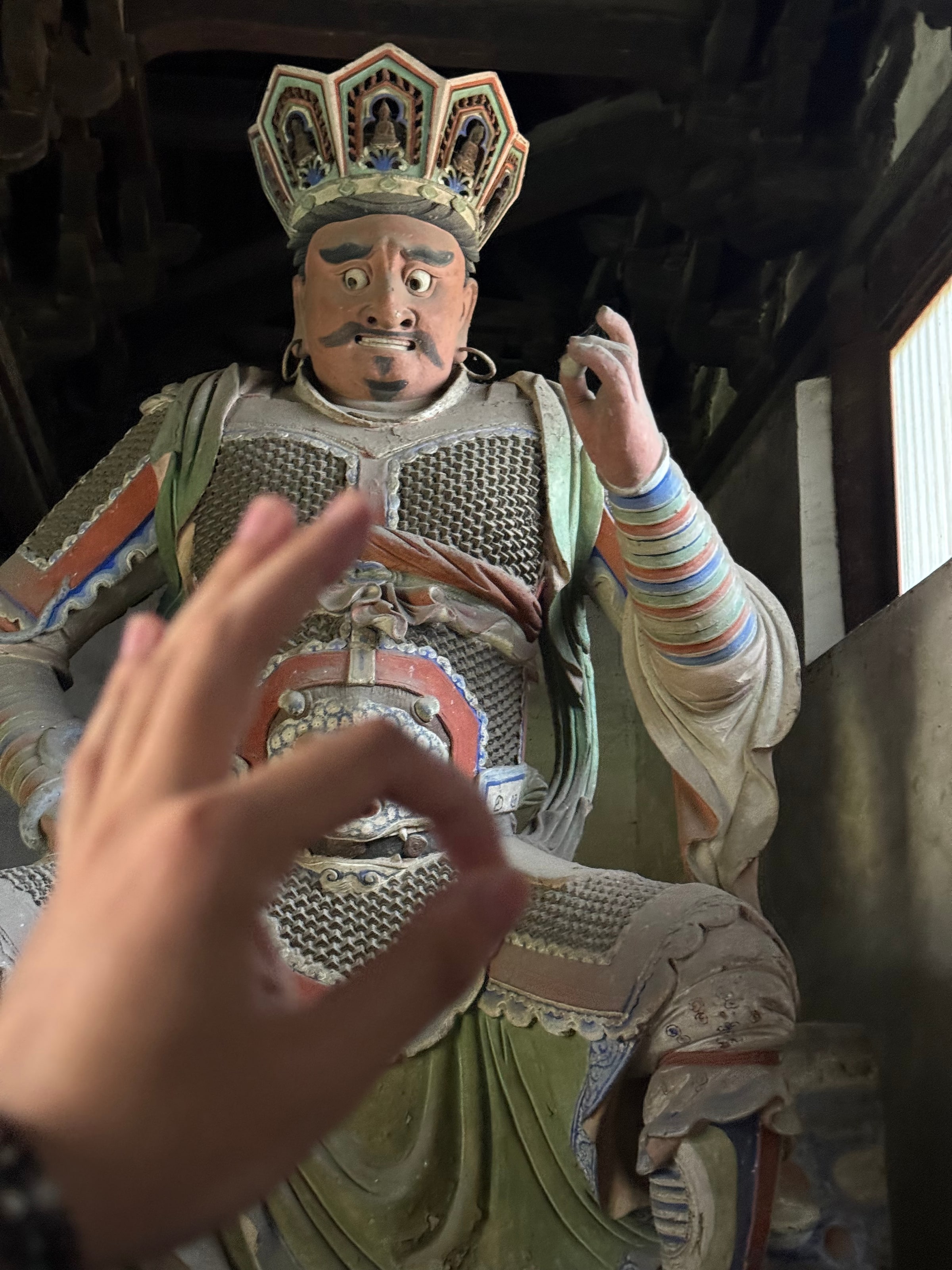 天王彩塑怒目持杵，我伸手比了个同款手势逗他，一张严肃了千年的脸。